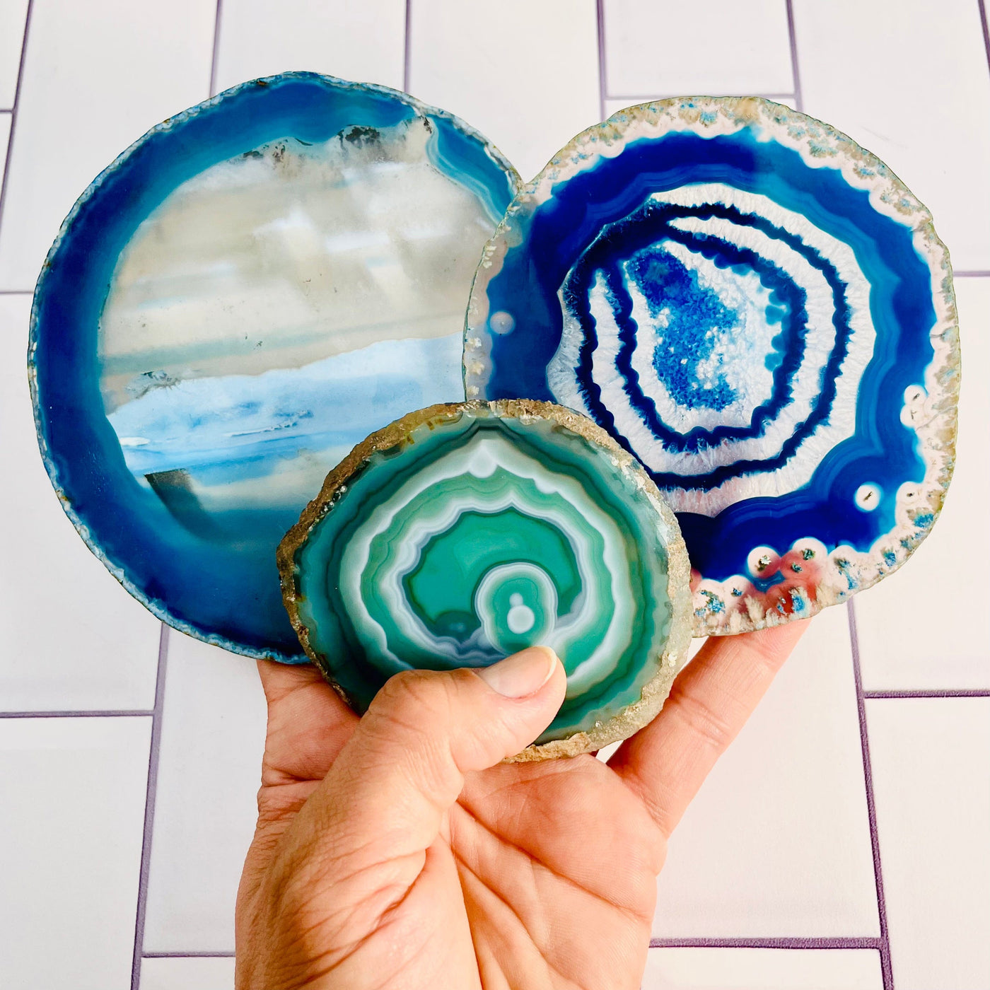 Frontal view of Set of 3 Agate Slices - Dyed Blue and Green, fanned out while held in woman's hand.