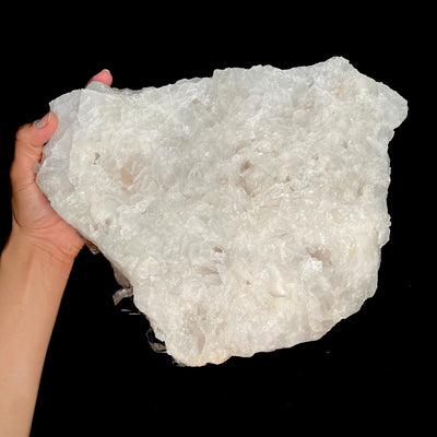 Bottom view of the Rough Crystal Quartz Large Cluster, held on the left side by a woman's hand.