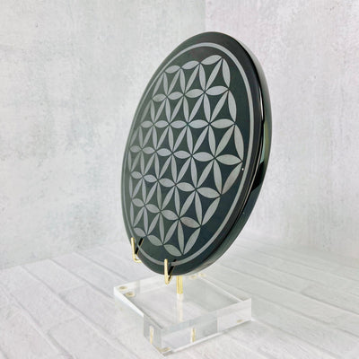 Side frontal angled view of Black Obsidian Flower of Life Plate on a stand.
