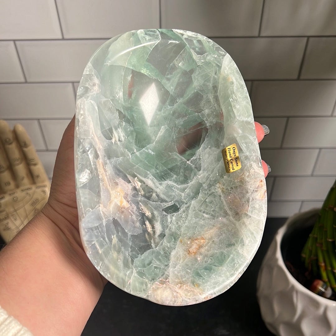 Green fluorite bowl held up by a woman's hand.