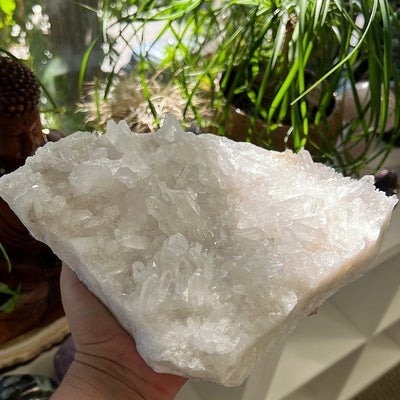 Large triangular shaped crystal cluster held in a woman's hand.