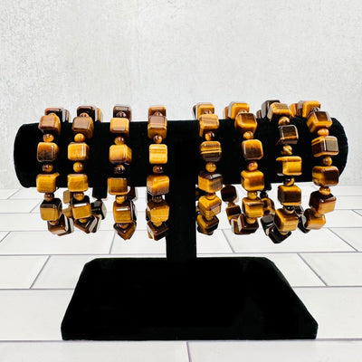 8 Tiger's Eye cubed bracelets displayed on black bracelet display.