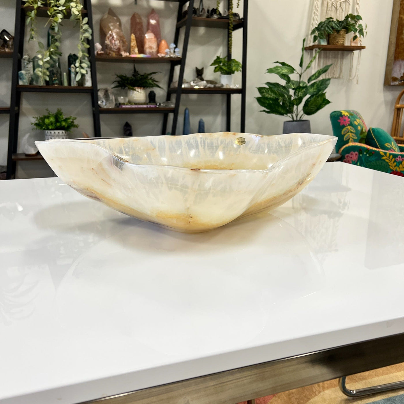 Large mexican onyx bowl displayed on a counter top. It is shades of cream, tan, and brown.