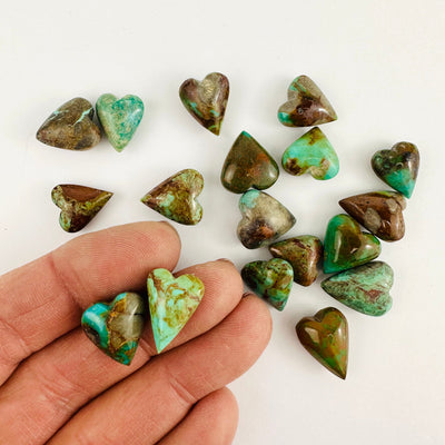 Turquoise hearts on a white background with two held in a hand.