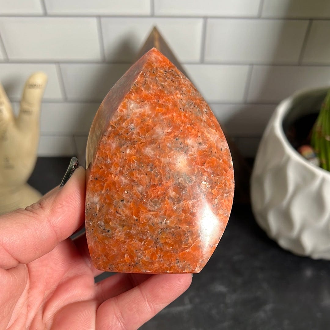 Orange calcite flame held in a woman's hand.