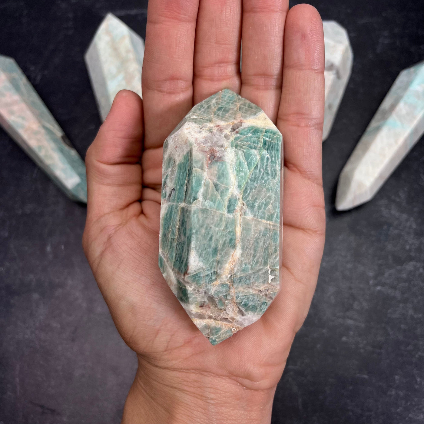 Amazonite Polished Double Terminated Point, in the weight range of 150g-200g, laying in palm of woman's hand.