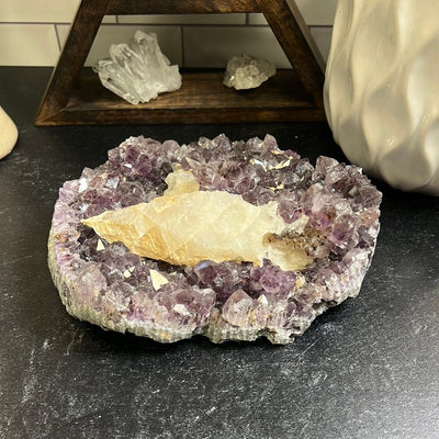 Large amethyst cluster with white calcite formations on it on a black background.