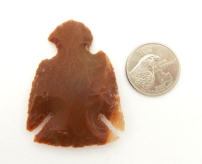 Eagle shaped Jasper Arrowhead next to quarter for size reference
