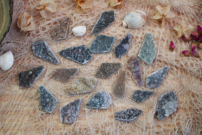 multiple Large Spearhead Druzy Cabochons displayed on brown background to show various colors textures formations and sizes