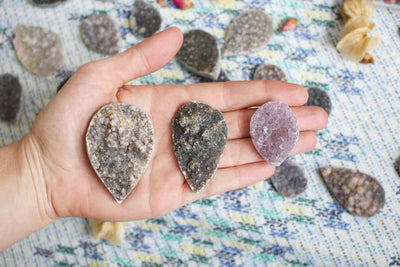 hand holding up 3 Large Teardrop Druzy Cabochons with others in the background