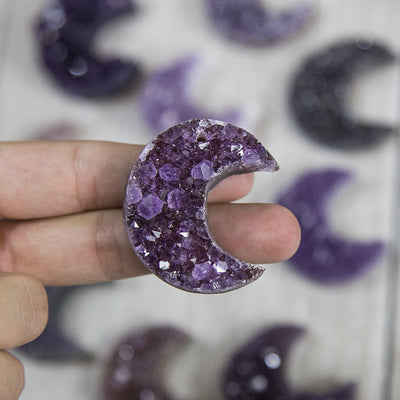 One amethyst moon in a woman's hand taking up two fingers.