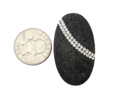 oval lava rock bead with rhinestones next to a quarter on white background