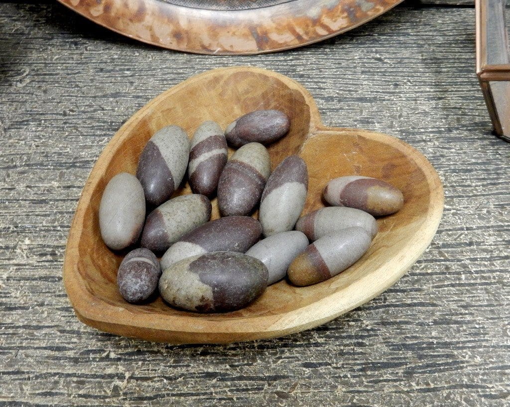 lingam stones inside a wooden heart bowl