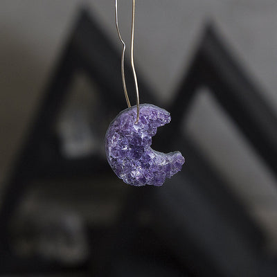 One drilled amethyst moon hanging from a wire.