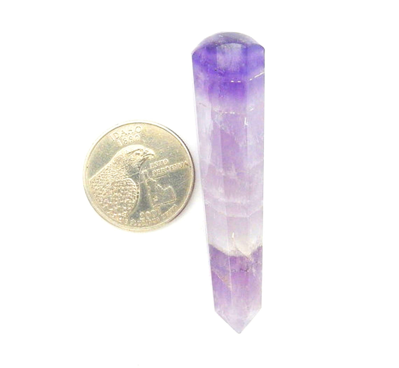 amethyst massage wand next to a quarter for size reference on white background