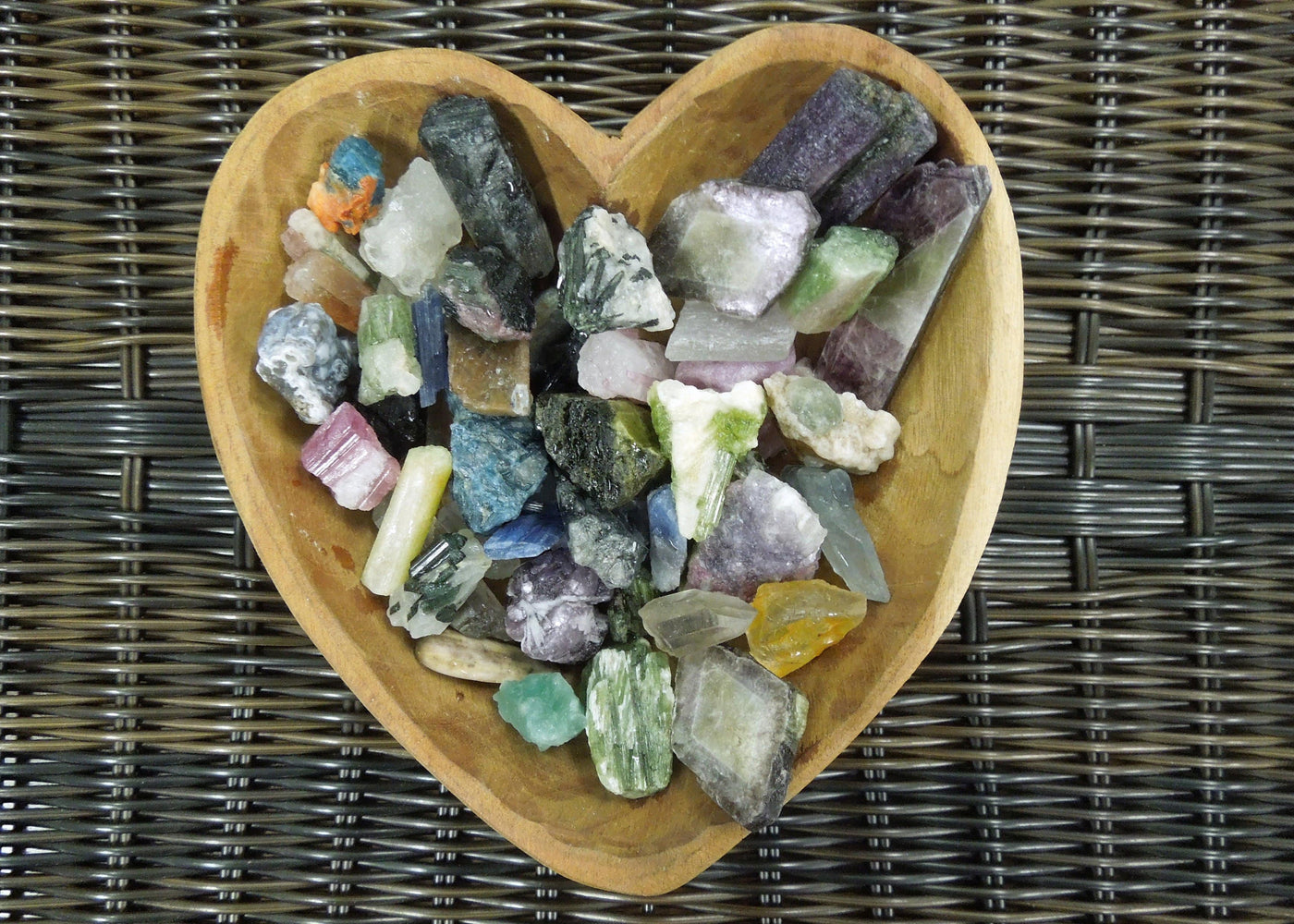 Assorted minerals in a heart shaped wood bowl.