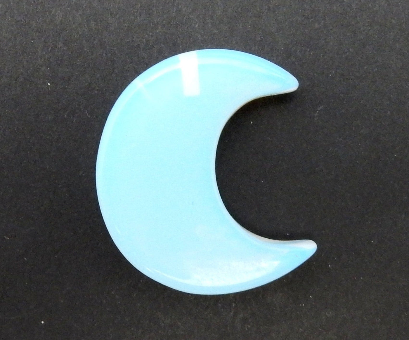 Opalite Half Crescent Moon - Drilled displayed on a black surface.