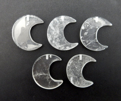 Five Crystal Quartz Half Crescent Moons - Drilled, displayed on a black surface.
