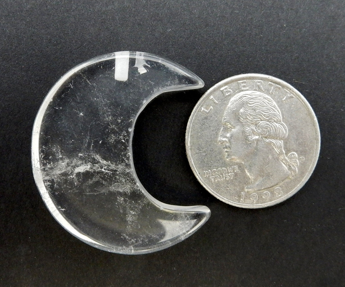 Crystal Quartz Half Crescent Moon - Drilled displayed next to a quarter for size reference.