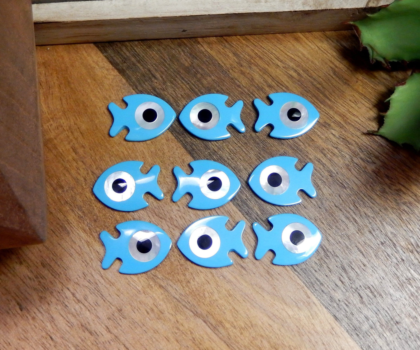 Multiple Fish with Mother of Pearl Eye Accent lined up on a brown background.