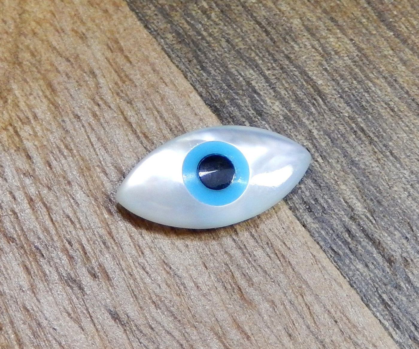 up close shot of pother of pearl Greek eye on wooden background