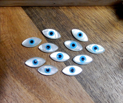 11 mother of pearl Greek eyes on wooden background