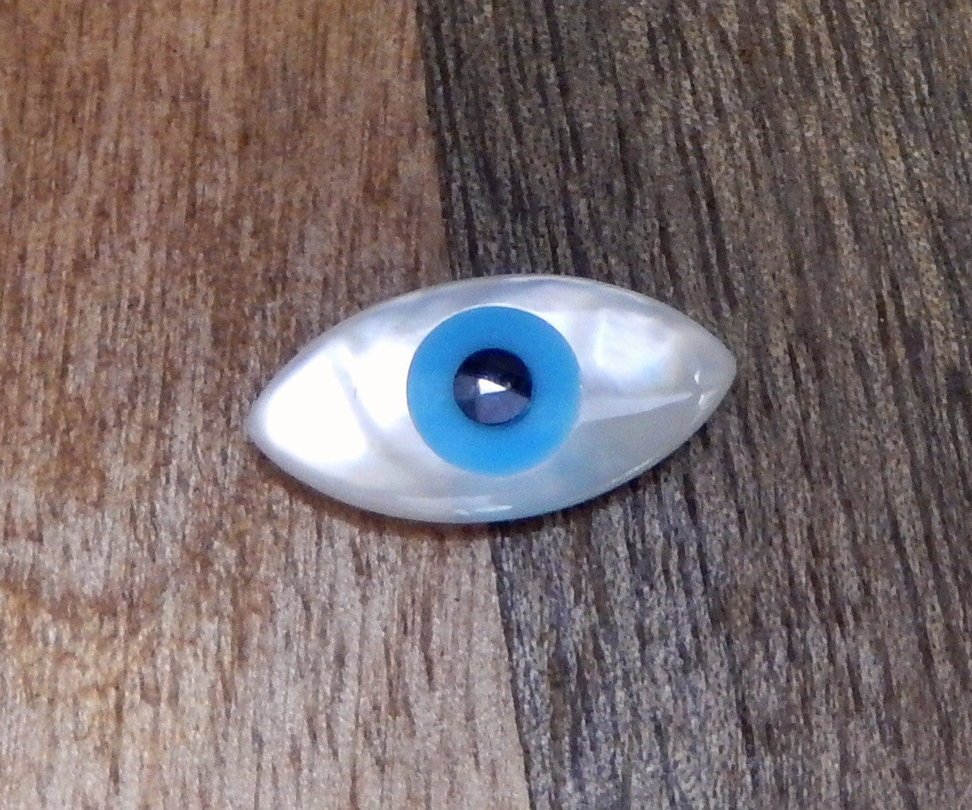 up close shot of mother of pearl Greek eyes on wooden background