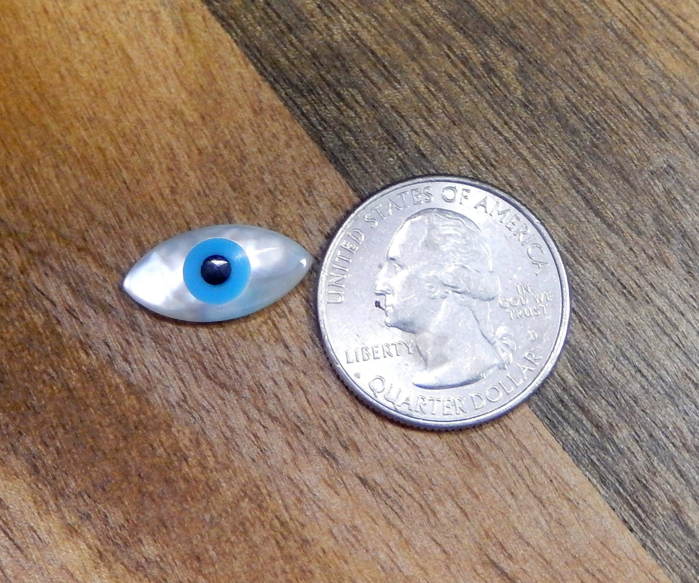 mother of pearl Greek eye next to a quarter for size reference