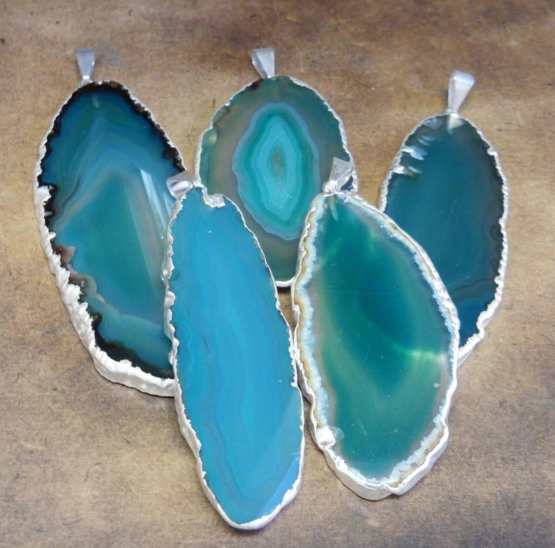 Picture of our green agate slice pendants being displayed on a dark brown background.