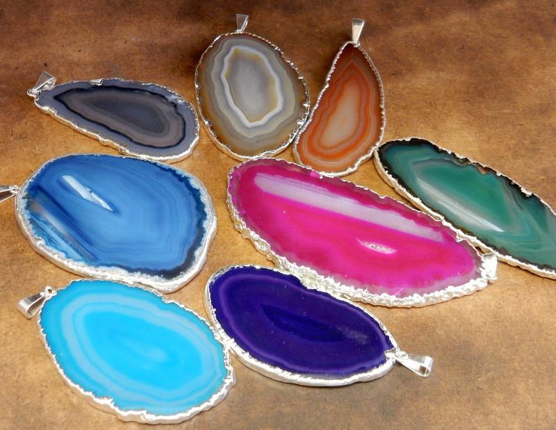 Picture of multiple options we have available for our agate slice pendants, on a dark brown background. 