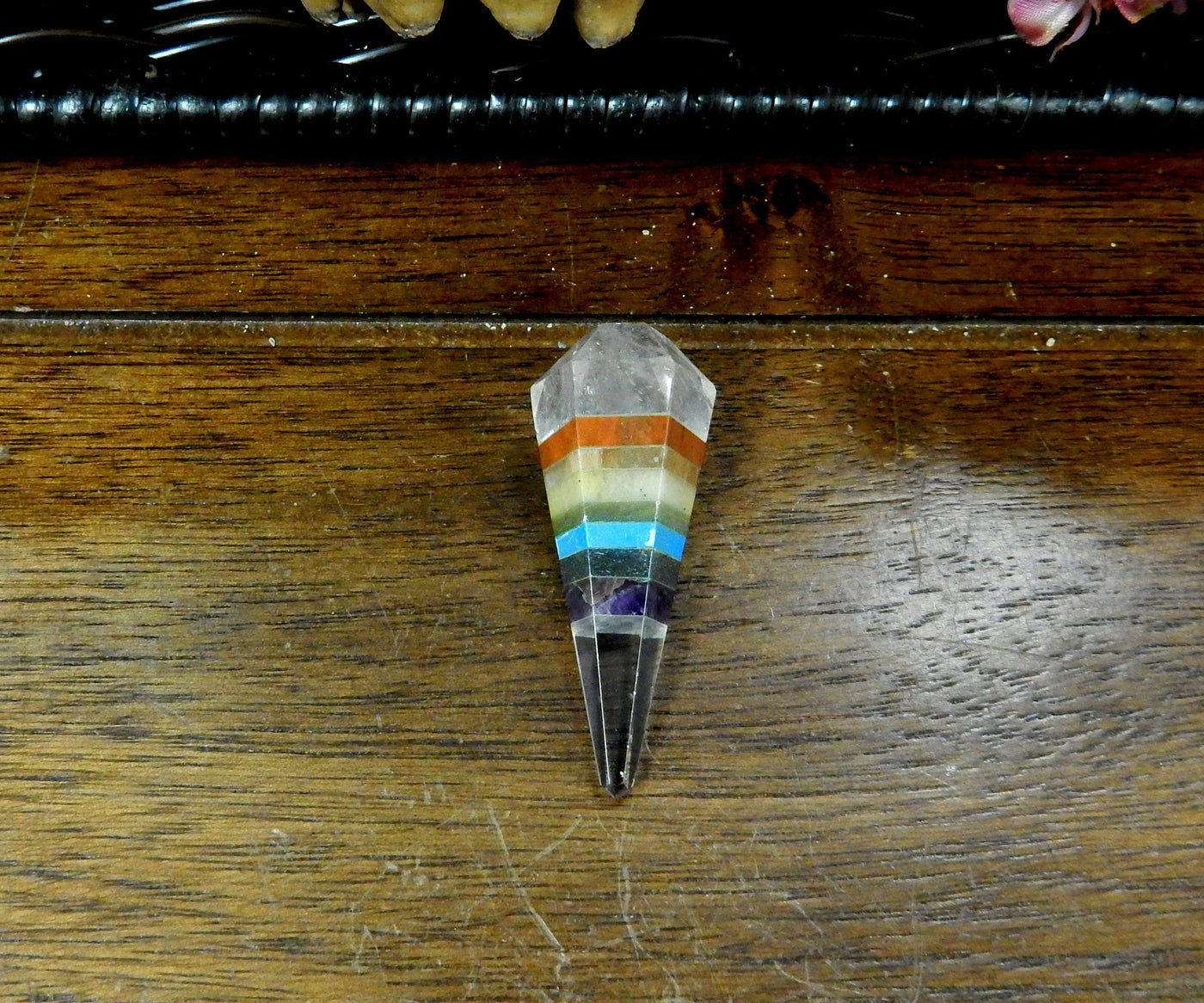 seven chakra pendulum point with no chain on a wood background.
