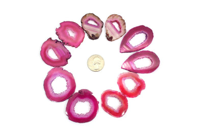 5 pairs of pink durzy agate slices surrounding a quarter for size reference on white background