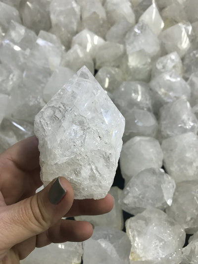 Crystal Quartz Semi Polished Points in the background with one in a hand for size reference