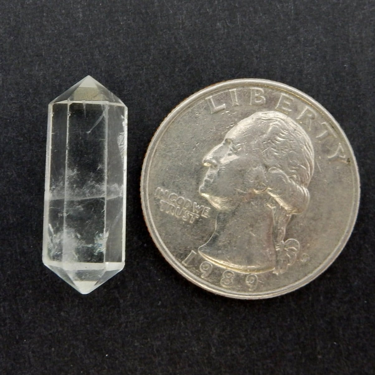 Single Petite Crystal Quartz Double Terminated Pencil Point next to a quarter for size comparison