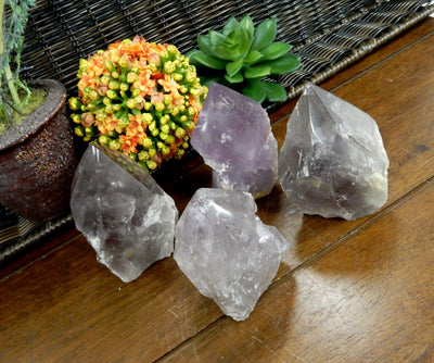 Angled top view of 4 Raw Amethyst Semi Polished Points on wooden table with various decorations in the background