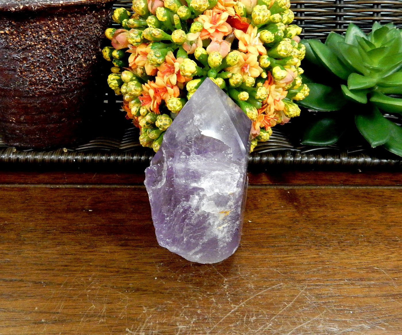 1 Raw Amethyst Semi Polished Point on wooden table with various decorations in the background