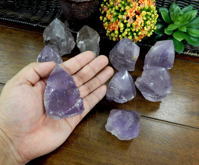 Hand holding 1 Raw Amethyst Semi Polished Point with 8 others in the background