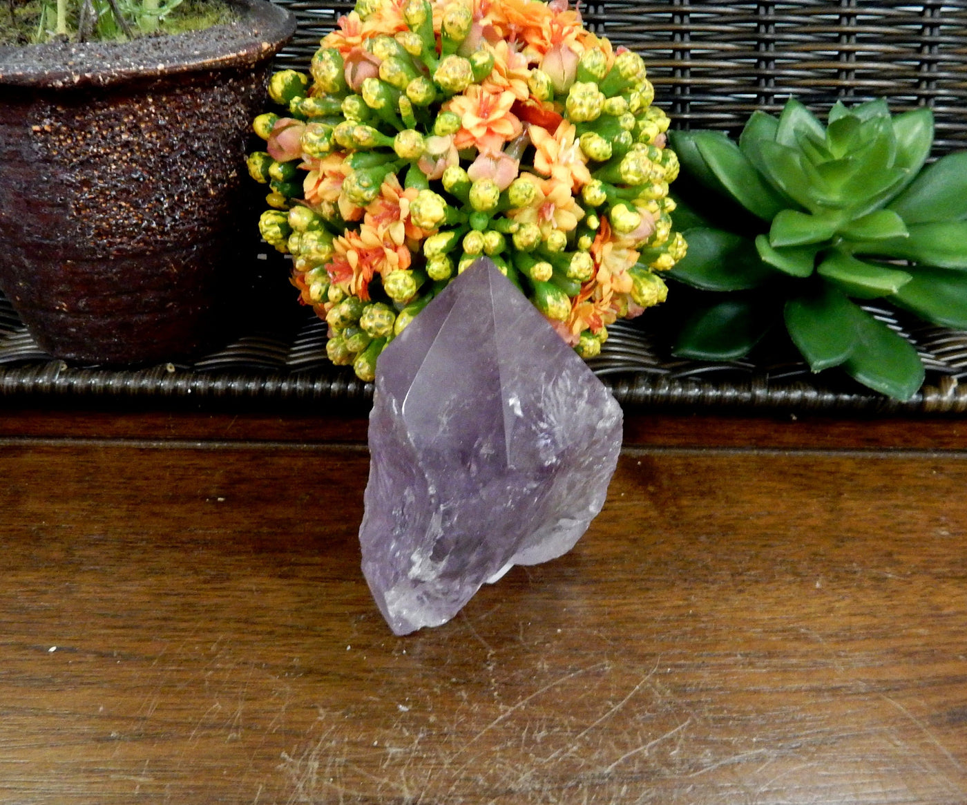 1 Raw Amethyst Semi Polished Point on wooden table with various decorations in the background