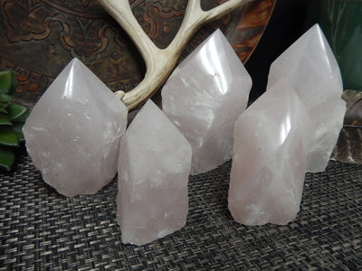 5 Rose Quartz Semi Polished Points of different sizes in front of decorations