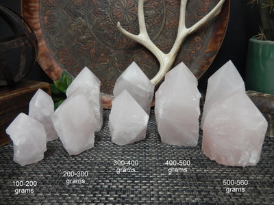 Rose Quartz Semi Polished Points in various weights in front of decorations