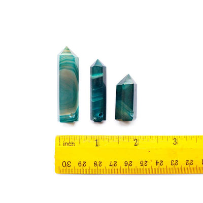 3 pieces of Teal Agate Drilled Pencil Points next to a ruler for an estimate size. Measurement can vary between 1" and 2"