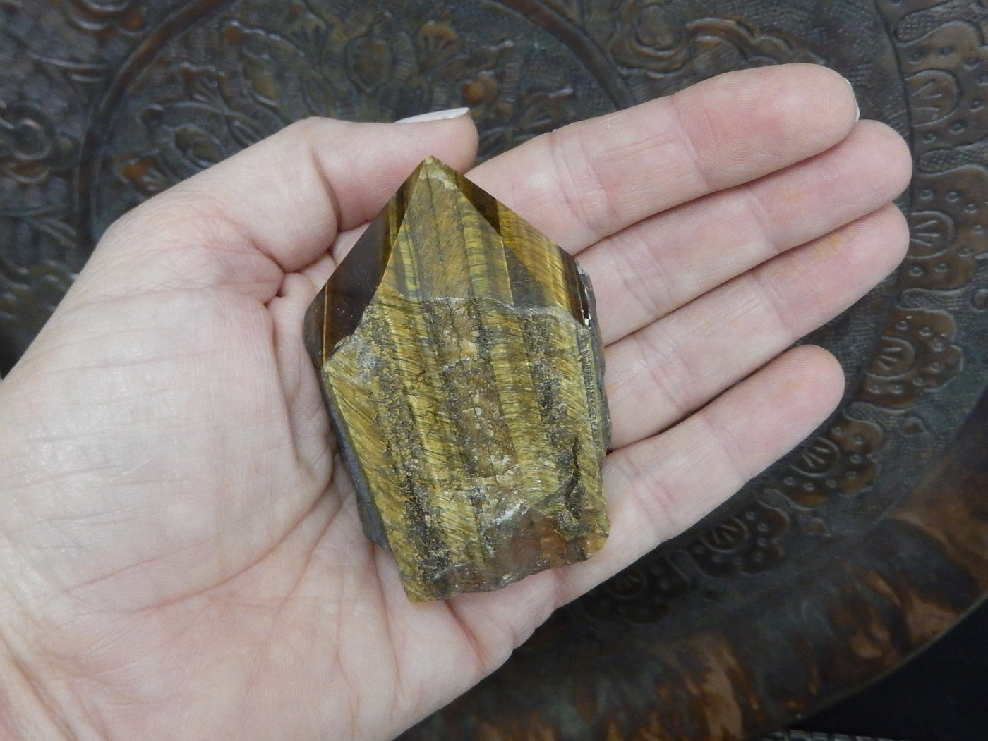 tiger eye polished point in a hand.