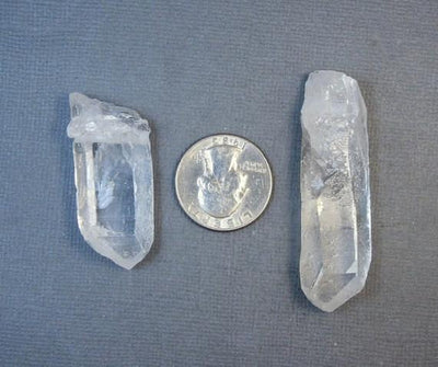 2 Top Side Drilled Crystal Point, in the Middle a Quarter on Gray Background.