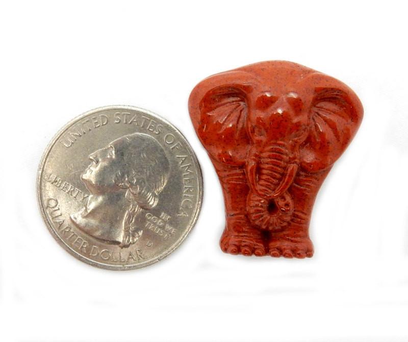 Red Jasper Elephant Cabochon next to quarter for size reference on white background