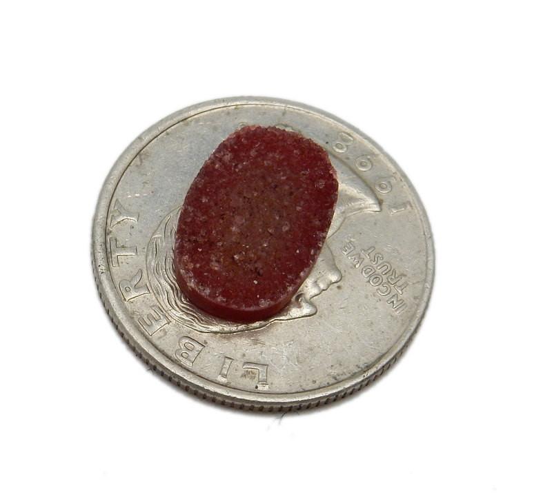 Red Oval Druzy on top of quarter for size reference on white background