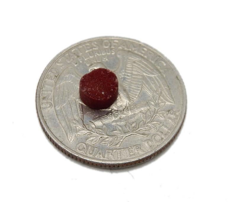 Red Round Druzy on top of quarter for size comparison on white background