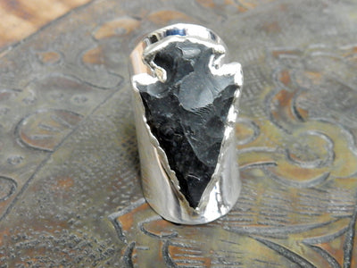 Black Obsidian Silver edged Arrowhead set on Adjustable Silver Electroplated Cigar Band Ring on brown background