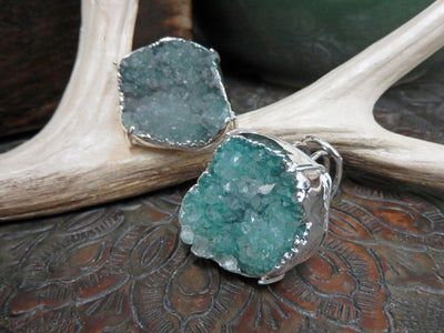 front and side view of teal druzy rings in silver