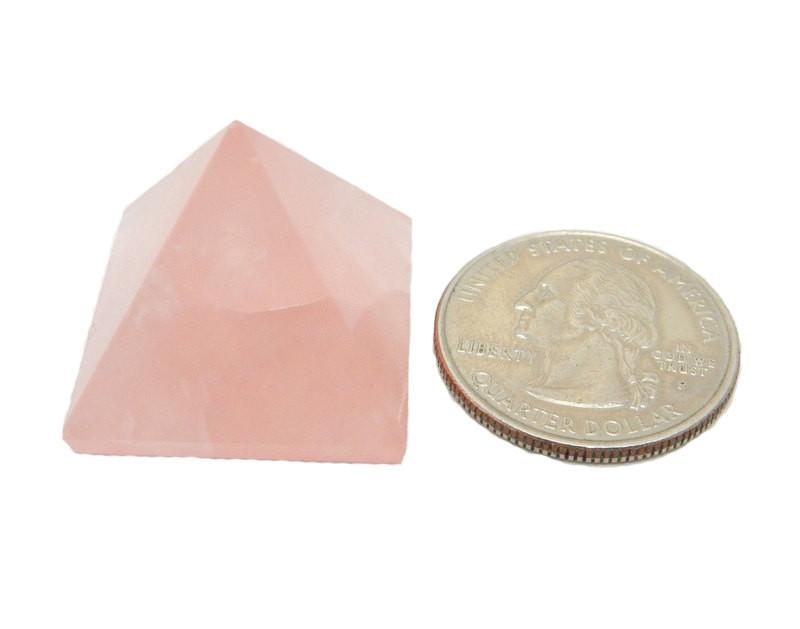 Rose Quartz Pyramid next to a quarter for size reference on white background