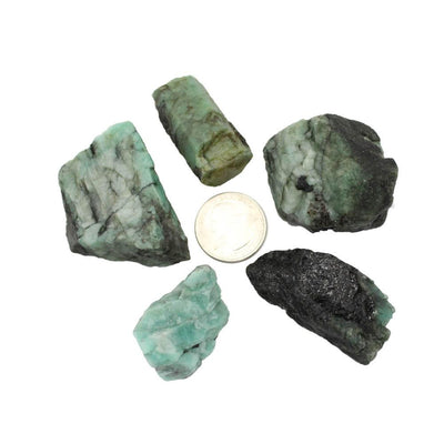 Rough Emerald Nuggets surrounding a quarter for size comparison